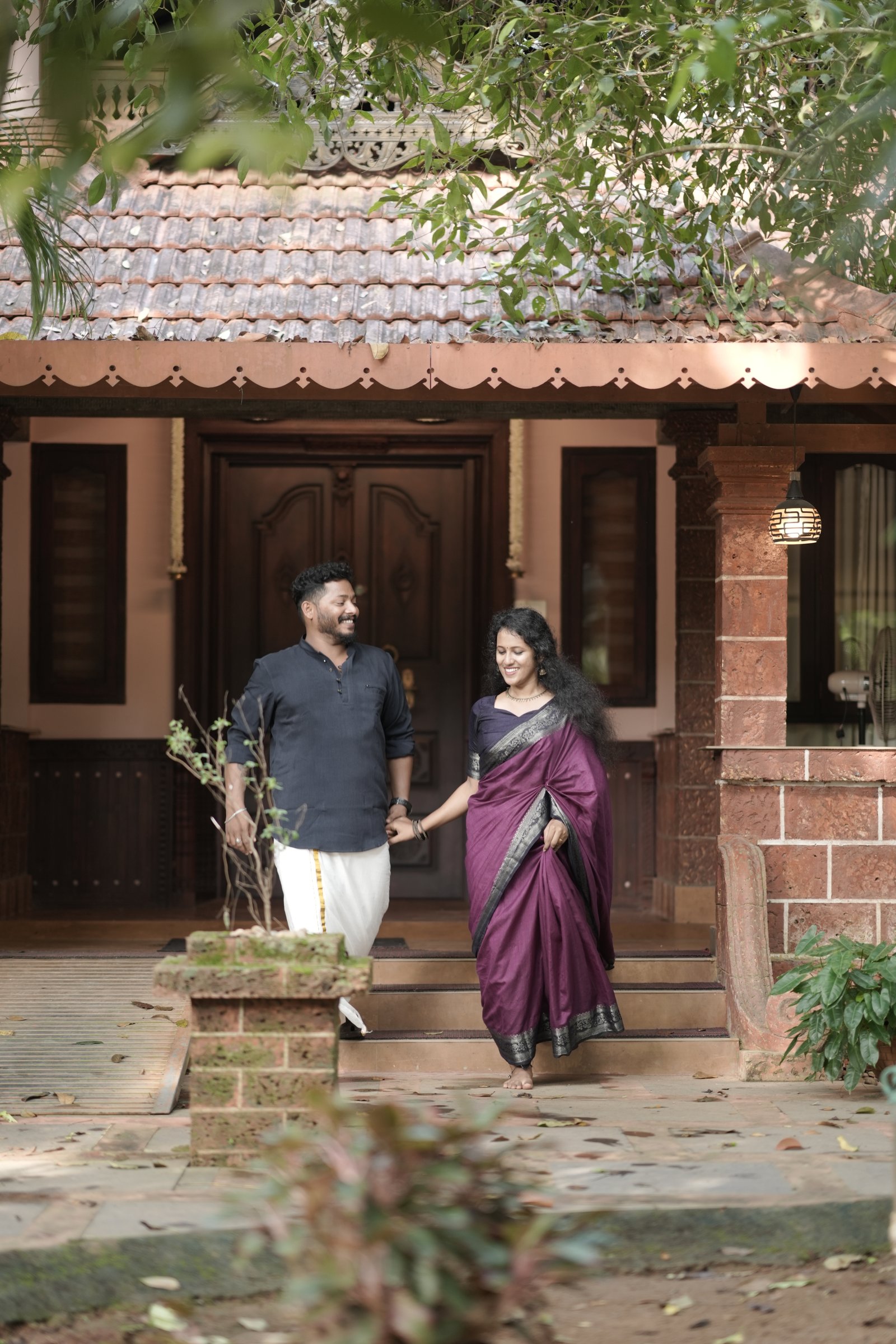Rahul holding Sruthy's hand outside their traditional home